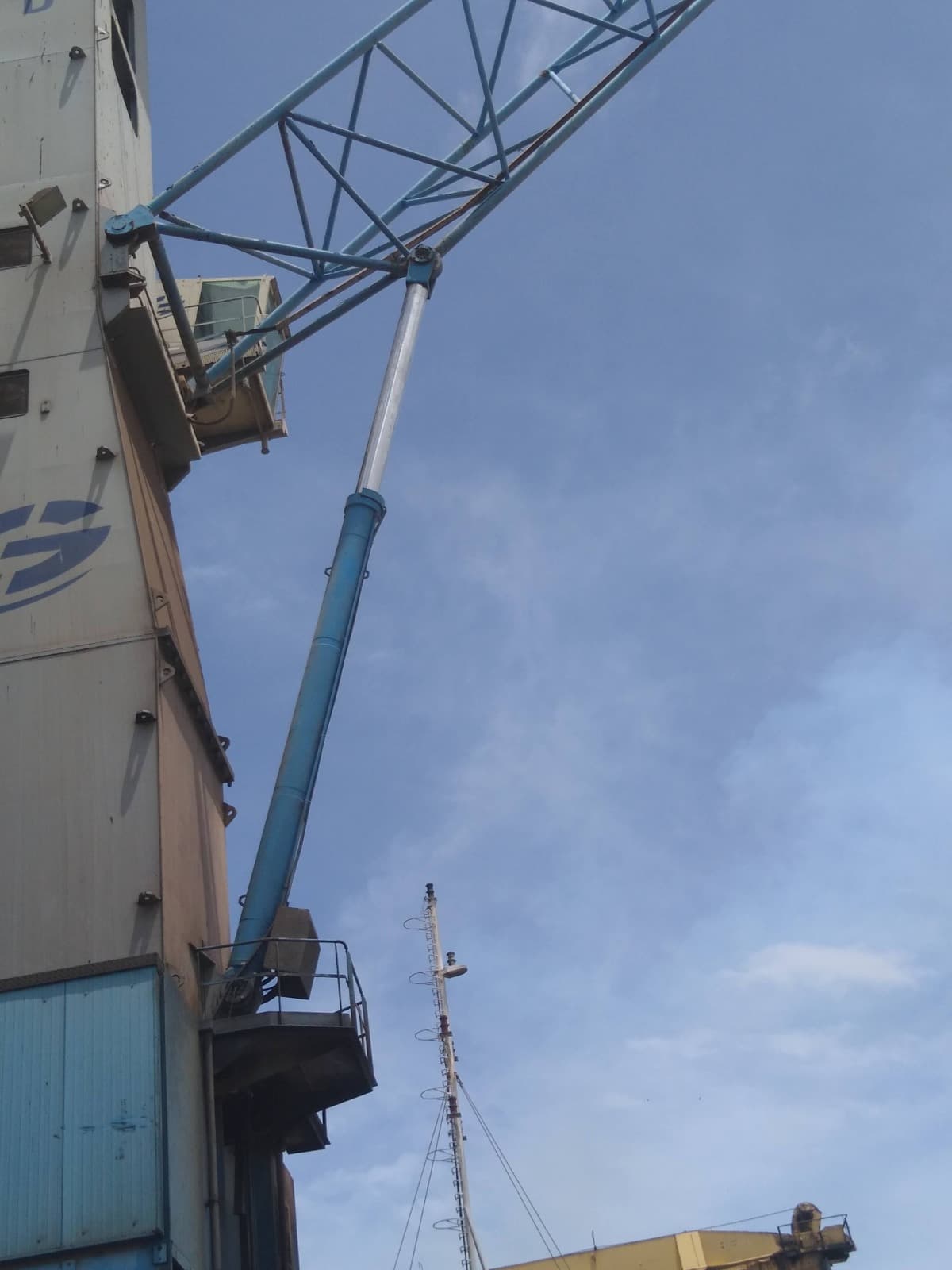 Vue en contre-plongée du bras d'une grue portuaire contre un ciel bleu